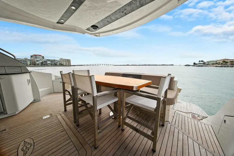 Slide: The Image of 2014 Marquis 630 Sport Yacht deck with seating, overlooking serene waterfront and cityscape. - 19