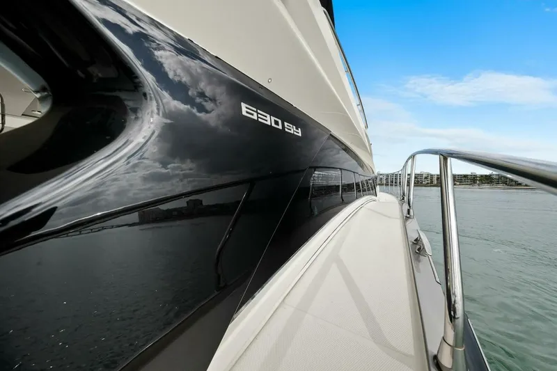 Slide: The Image of 2014 Marquis 630 Sport Yacht on water, sleek design, reflecting sky and clouds. - 24