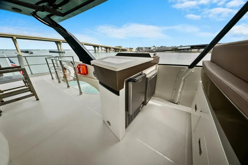 Slide: The Image of 2014 Marquis 630 Sport Yacht deck with seating, mini fridge, and scenic water view. - 33