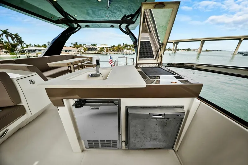 Slide: The Image of 2014 Marquis 630 Sport Yacht outdoor kitchen with sink and grill, overlooking serene waterfront. - 34
