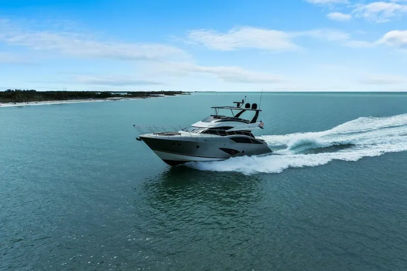 Slide: The Image of 2014 Marquis 630 Sport Yacht cruising on open water under a clear blue sky. - 69