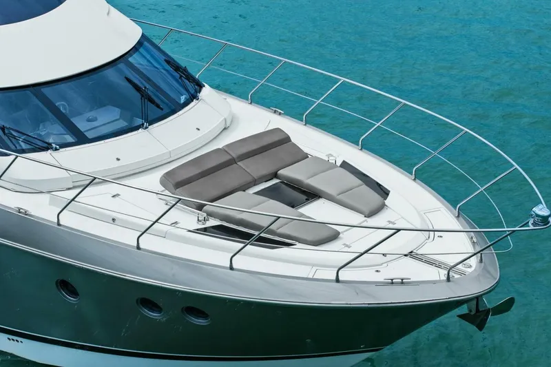 Slide: The Image of 2014 Marquis 630 Sport Yacht on clear blue water, featuring sleek design and sunbathing area. - 76