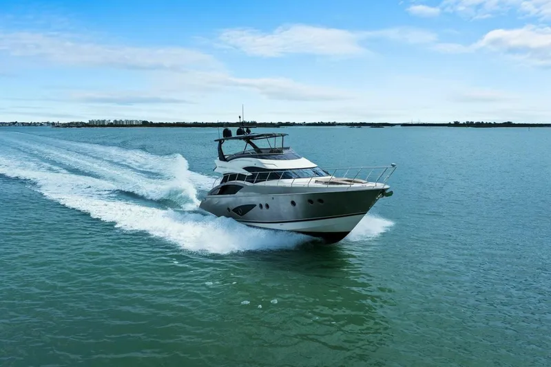 Slide: The Image of 2014 Marquis 630 Sport Yacht cruising on open water under a clear blue sky. - 81
