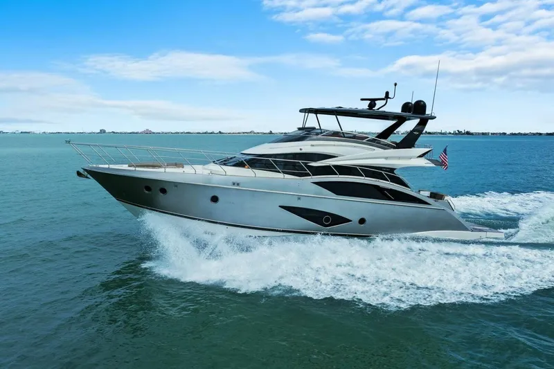 Slide: The Image of 2014 Marquis 630 Sport Yacht cruising on open water under a clear blue sky. - 84