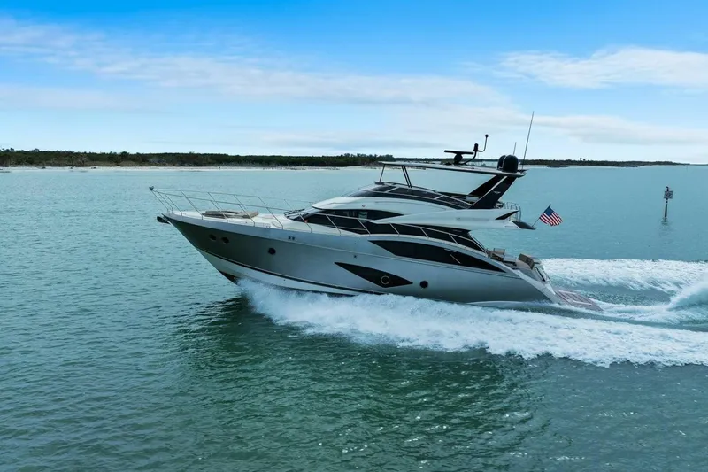Slide: The Image of 2014 Marquis 630 Sport Yacht cruising on open water under clear blue skies. - 86