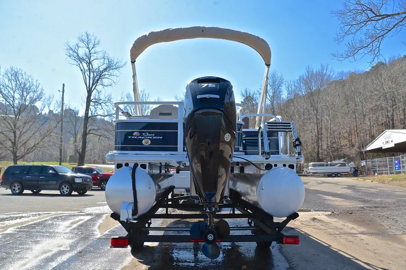 Slide: The Image of 2024 Sun Tracker Bass Buggy 18 DLX pontoon boat on trailer, parked outdoors. - 13