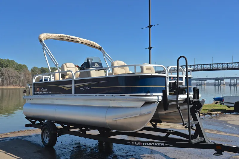 Slide: The Image of 2024 Sun Tracker Bass Buggy 18 DLX pontoon boat on trailer by a lake. - 16