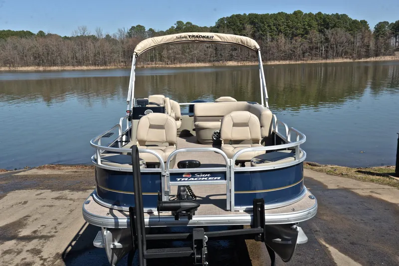 Slide: The Image of 2024 Sun Tracker Bass Buggy 18 DLX pontoon boat on a serene lake. - 17