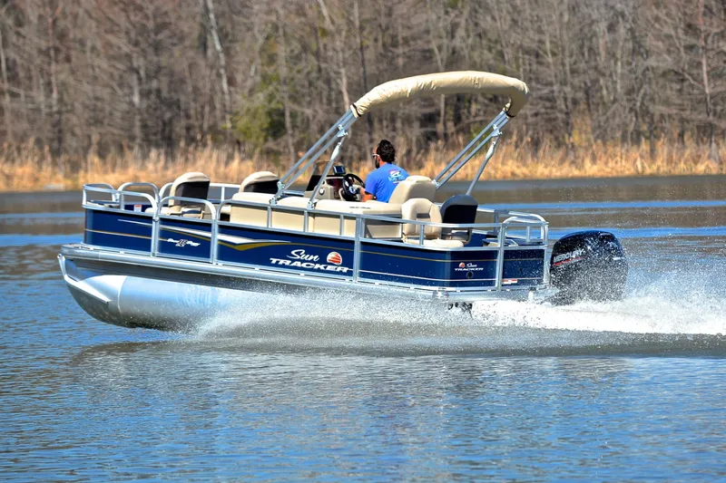 Slide: The Image of 2024 Sun Tracker Bass Buggy 18 DLX pontoon boat cruising on a lake. - 4