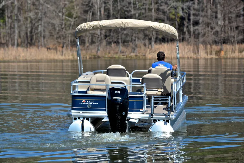 Slide: The Image of 2024 Sun Tracker Bass Buggy 18 DLX pontoon boat cruising on a calm lake. - 7