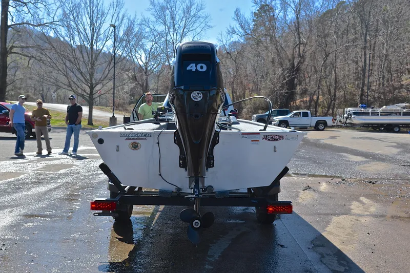 Slide: The Image of 2017 Bass Tracker Pro 16 boat on trailer, parked outdoors with people nearby. - 13