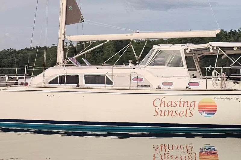 Slide: The Image of 2005 Catalina Morgan 440 sailboat named "Chasing Sunsets" on calm water. - 2