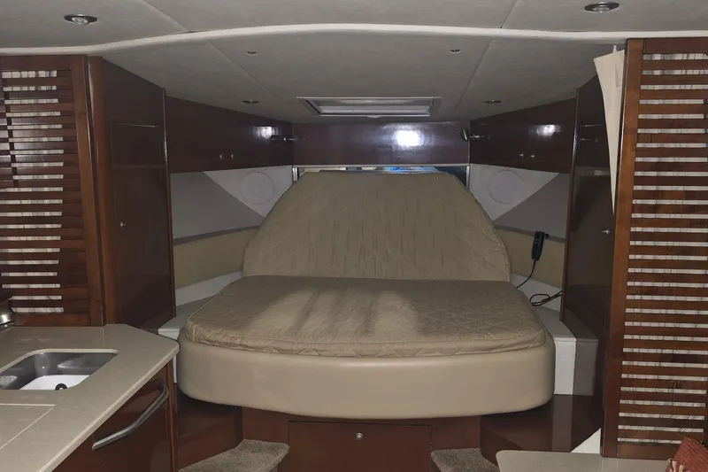 Slide: The Image of 2009 Sea Ray Sundancer 350 cabin interior with bed, wood paneling, and kitchenette. - 14