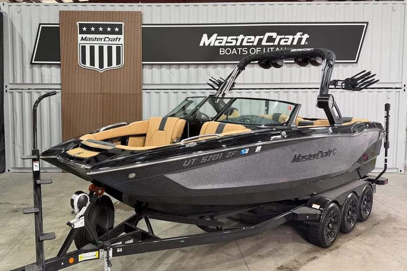 The Image of 2023 MasterCraft X24 boat on trailer in showroom, sleek design, luxury seating. - 1