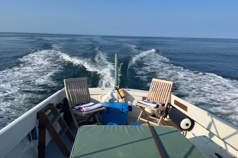 Slide: The Image of 1970 Brownell Cuttyhunk boat cruising on open sea with deck chairs and cooler. - 6