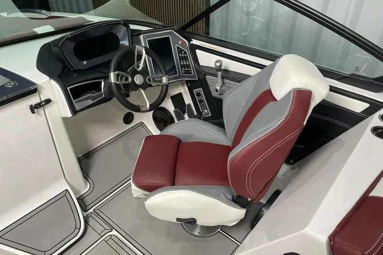 Slide: The Image of 2023 MasterCraft X26 boat interior with maroon and white captain's seat, steering wheel, and control panel. - 11