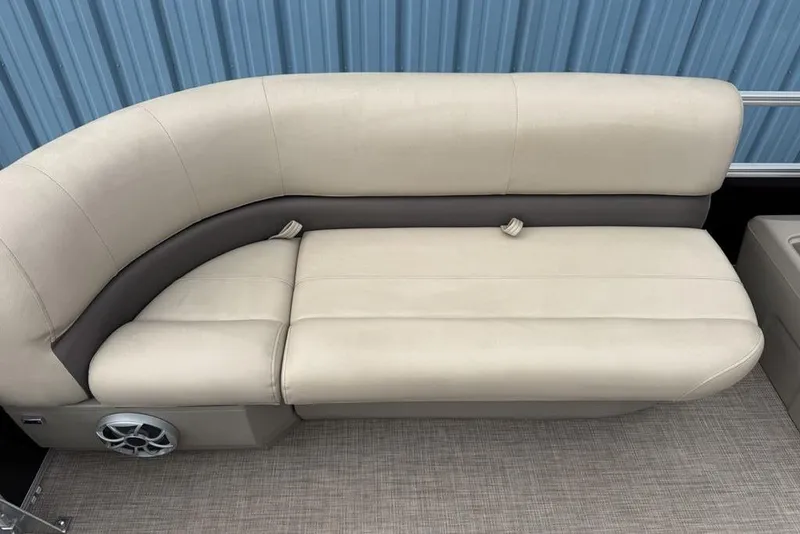 Slide: The Image of 2024 Sun Tracker Party Barge 16 DLX beige seating with speaker, against blue backdrop. - 11