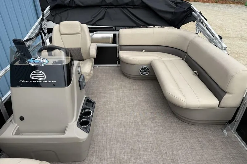 Slide: The Image of 2024 Sun Tracker Party Barge 16 DLX interior with beige seating and steering console. - 14
