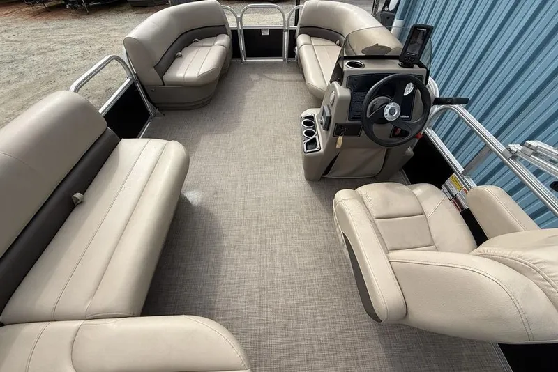 Slide: The Image of 2024 Sun Tracker Party Barge 16 DLX interior with beige seating and steering console. - 15