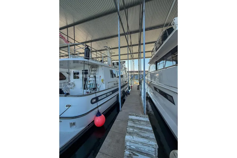 Slide: The Image of 2007 Nordic Tug 54 docked in a covered marina, side view with red buoy. - 17
