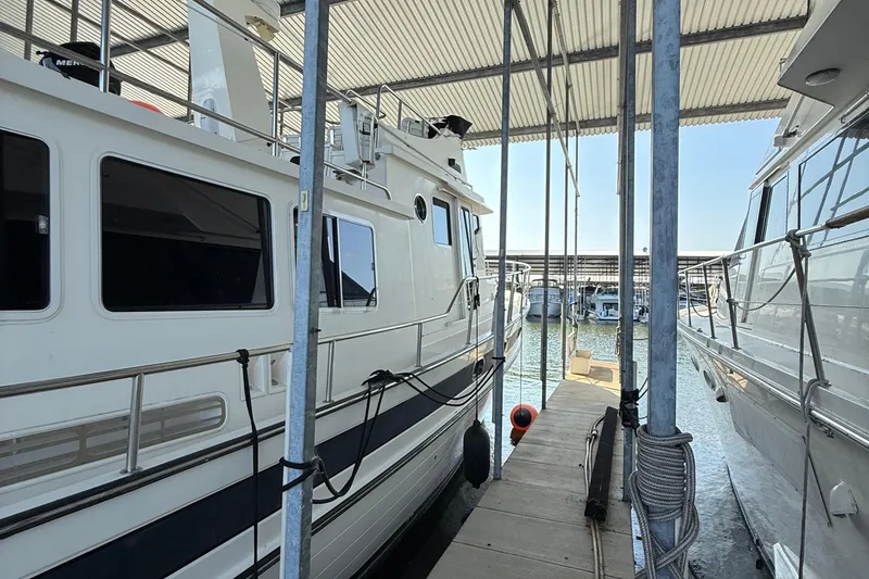 Slide: The Image of 2007 Nordic Tug 54 docked in a marina, sheltered under a metal roof. - 23