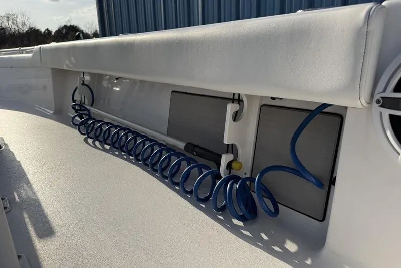 Slide: The Image of 2022 Sportsman Masters 247OE Bay Boat interior with coiled blue hose and storage compartments. - 28