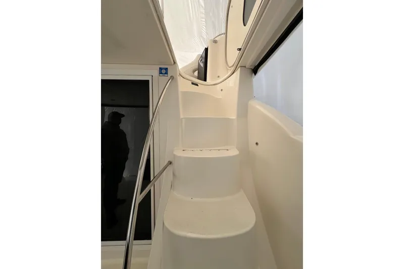 Slide: The Image of Staircase inside 2007 Meridian 391 Sedan yacht, featuring sleek white design and metal railing. - 36