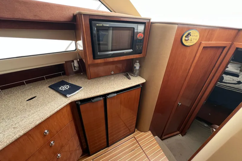 Slide: The Image of 2007 Meridian 391 Sedan yacht interior with microwave, fridge, and wooden cabinetry. - 58