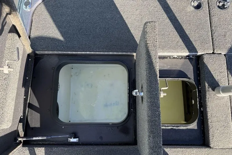 Slide: The Image of Open storage compartment on 2021 Skeeter ZXR21 boat, featuring carpeted interior and secure latch. - 26