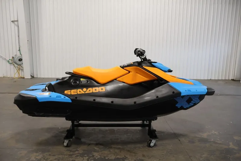 Slide: The Image of 2026 Sea-Doo Spark Trixx for 1, vibrant orange and blue design, in a garage setting. - 3