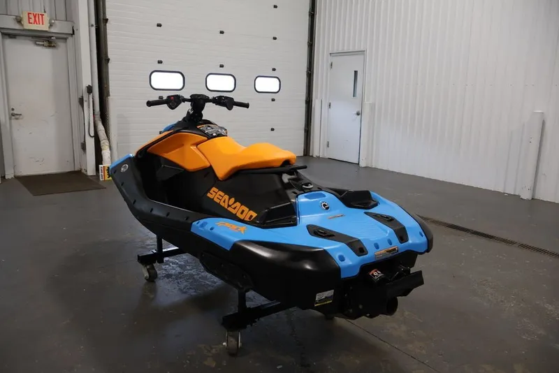 Slide: The Image of 2026 Sea-Doo Spark Trixx jet ski in blue and orange, displayed indoors. - 7