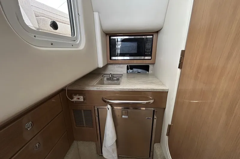Slide: The Image of 2017 Formula 350 Crossover Bowrider interior kitchenette with sink, microwave, and storage. - 15