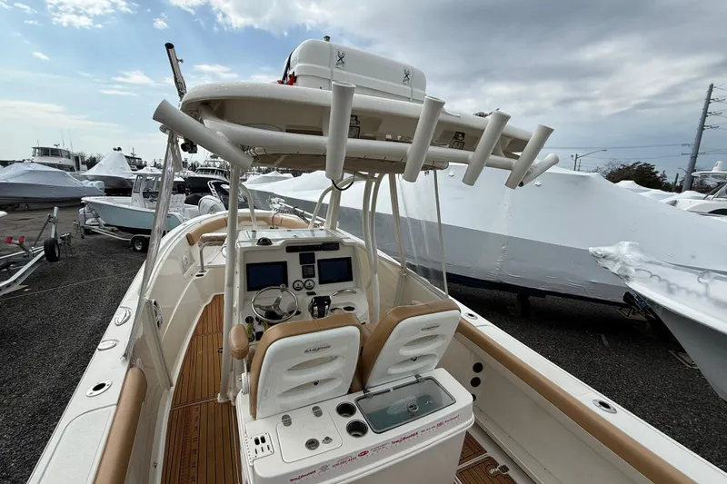 Slide: The Image of 2015 Sailfish 2860 CC boat with dual consoles and rod holders, docked under cloudy skies. - 5
