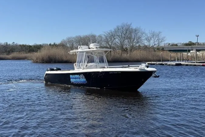 Slide: The Image of 2015 Sailfish 2860 CC boat on calm water, clear sky, and trees in the background. - 9