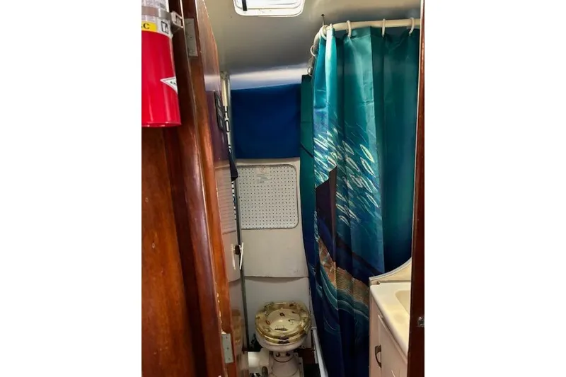 Slide: The Image of Interior of 1961 Hatteras 41 Convertible boat bathroom with shower curtain and toilet. - 6