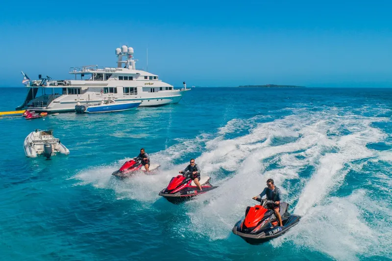 Slide: The Image of Jet skis racing near a 1988 Van Mill Custom yacht on clear blue ocean waters. - 106