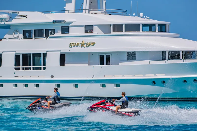 Slide: The Image of Two people on jet skis near a 1988 Van Mill Custom yacht named "Star Ship." - 108