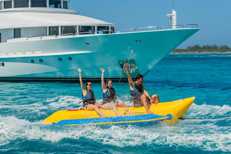 Slide: The Image of People enjoying a banana boat ride near a Van Mill Custom yacht, 1988 model, in clear blue waters. - 112