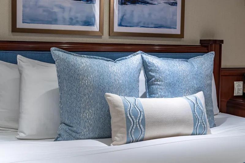 Slide: The Image of Luxurious bed with blue and white pillows, elegant wooden headboard, and framed artwork. - 74