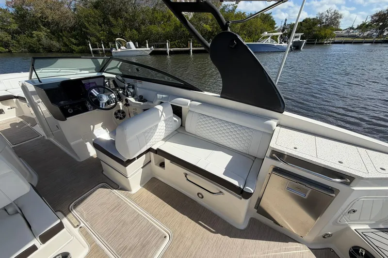 Slide: The Image of 2020 Sea Ray SDX 290 Outboard interior with luxurious seating and helm, docked by the water. - 26