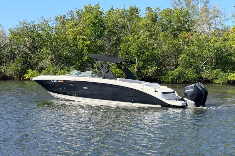 Slide: The Image of 2020 Sea Ray SDX 290 Outboard boat cruising on a calm river near lush greenery. - 4