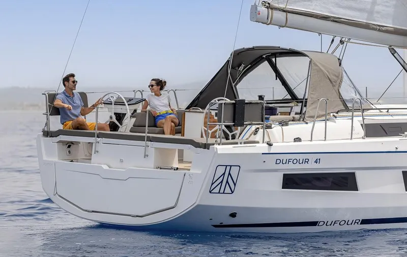 Slide: The Image of 2024 Dufour 41 sailboat on calm waters with two people on deck. - 3