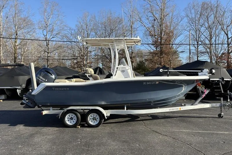 Slide: The Image of 2018 Tidewater 210 LXF boat on trailer, parked outdoors with trees in background. - 5