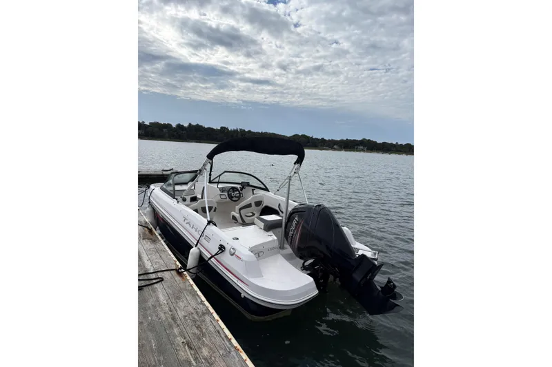 Slide: The Image of 2016 Tahoe 450 TS boat docked on a calm lake under a cloudy sky. - 4