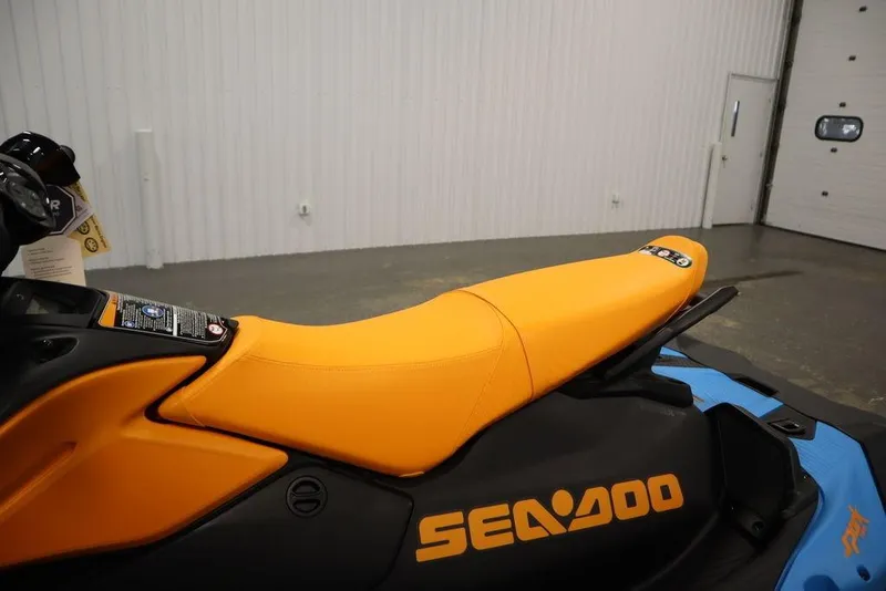 Slide: The Image of 2026 Sea-Doo Spark Trixx for 3 with vibrant orange seat in a showroom. - 16