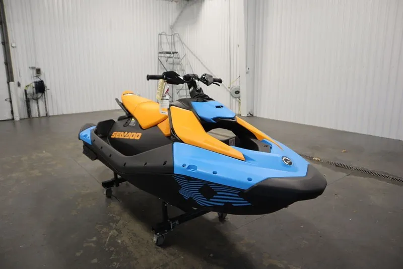 Slide: The Image of 2026 Sea-Doo Spark Trixx for 3 in vibrant blue and orange, displayed indoors. - 4