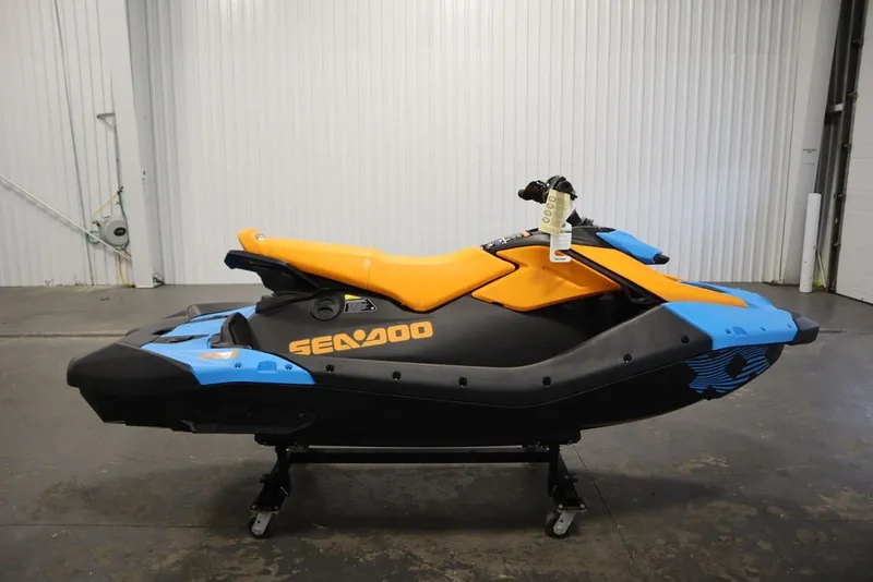 Slide: The Image of 2026 Sea-Doo Spark Trixx for 3, vibrant orange and blue design, in a showroom. - 5