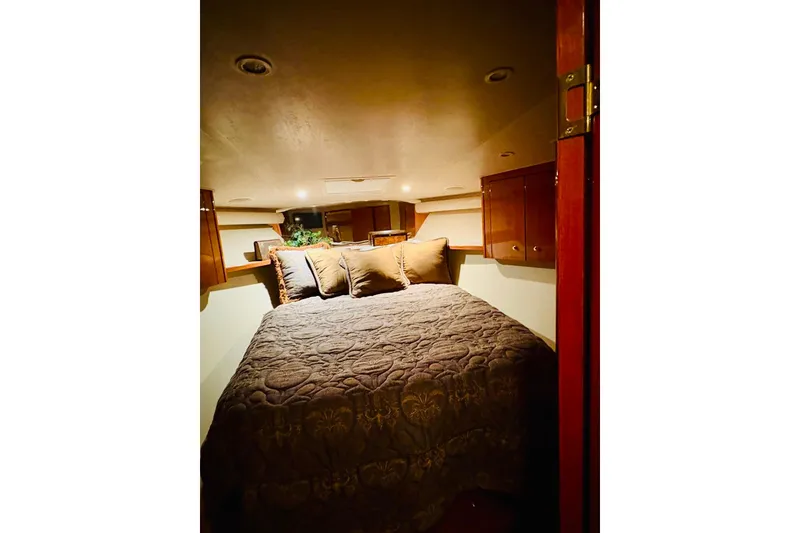 Slide: The Image of Cozy bedroom interior of 2004 Viking 45 Convertible yacht with plush bedding and wooden cabinets. - 9