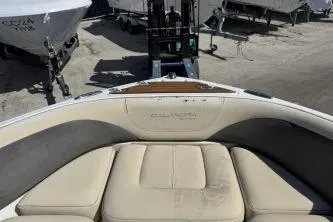 Slide: The Image of 2019 Bryant Calandra 23 boat interior with beige seating, docked near other boats. - 9