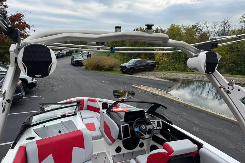 Slide: The Image of 2023 Malibu Wakesetter 20 VTX boat interior with red and white seating, parked outdoors. - 18
